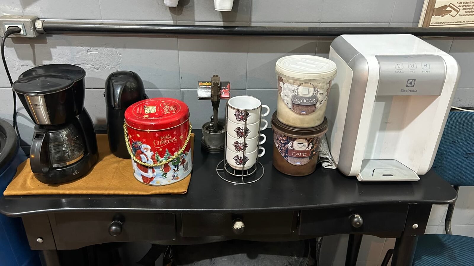 Espaço de espera da oficina com café, água e xícaras à disposição dos clientes