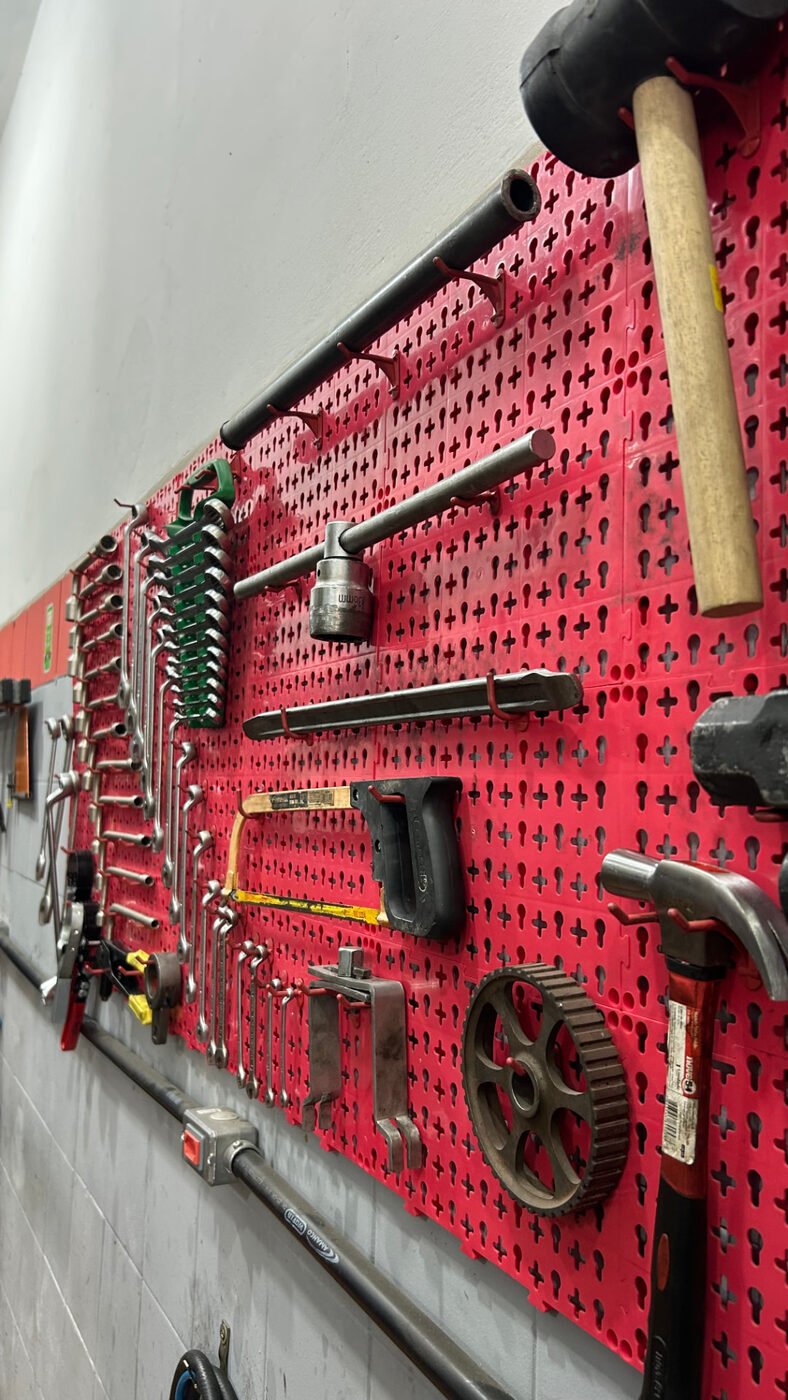 Painel vermelho com ferramentas organizadas na parede da oficina